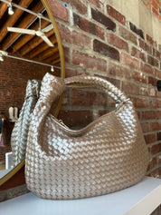 Champagne color woven shoulder bag with gold hardware and knits detail. 