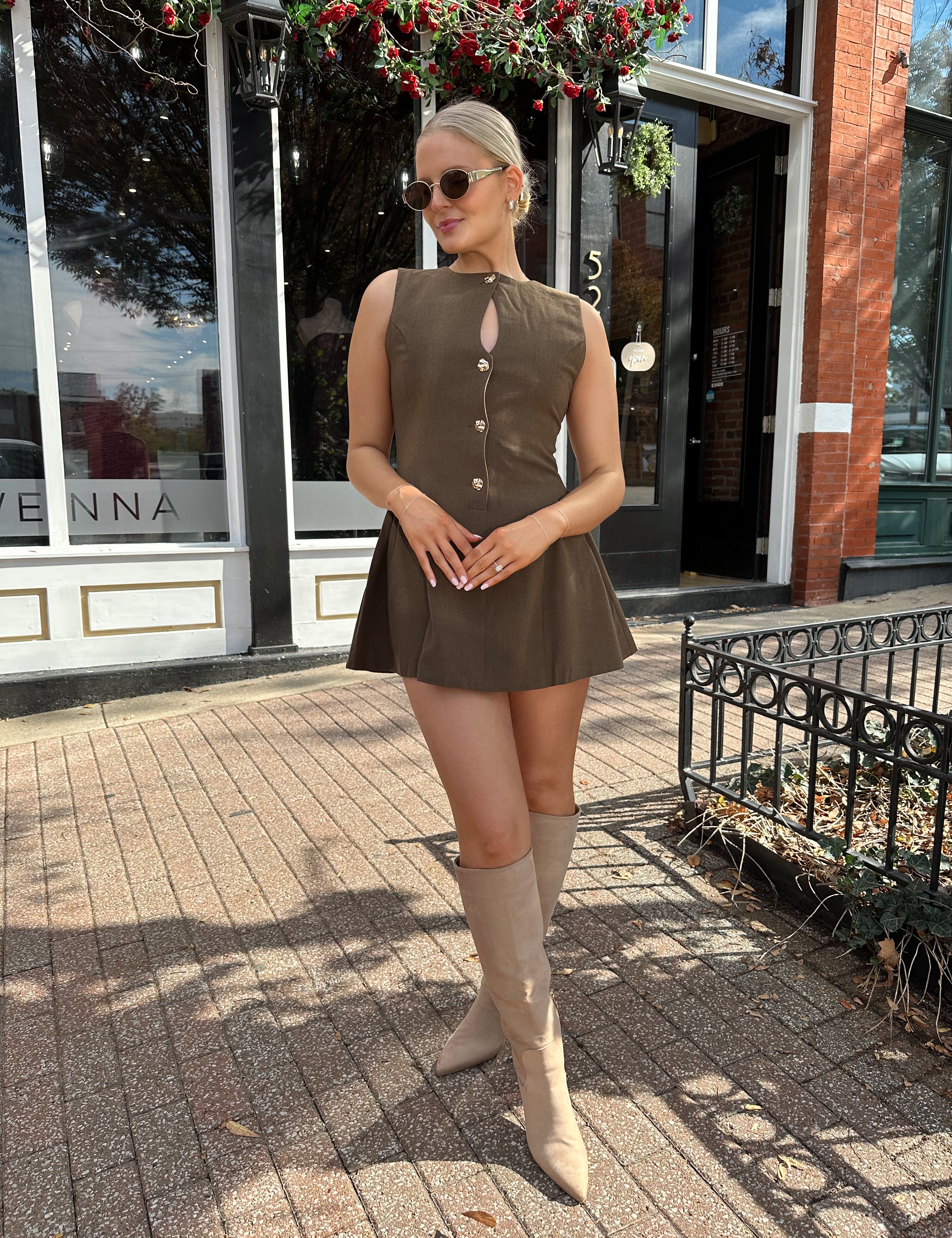 Woman wearing brown fit to flare mini dress with keyhole cutout and gold buttons.