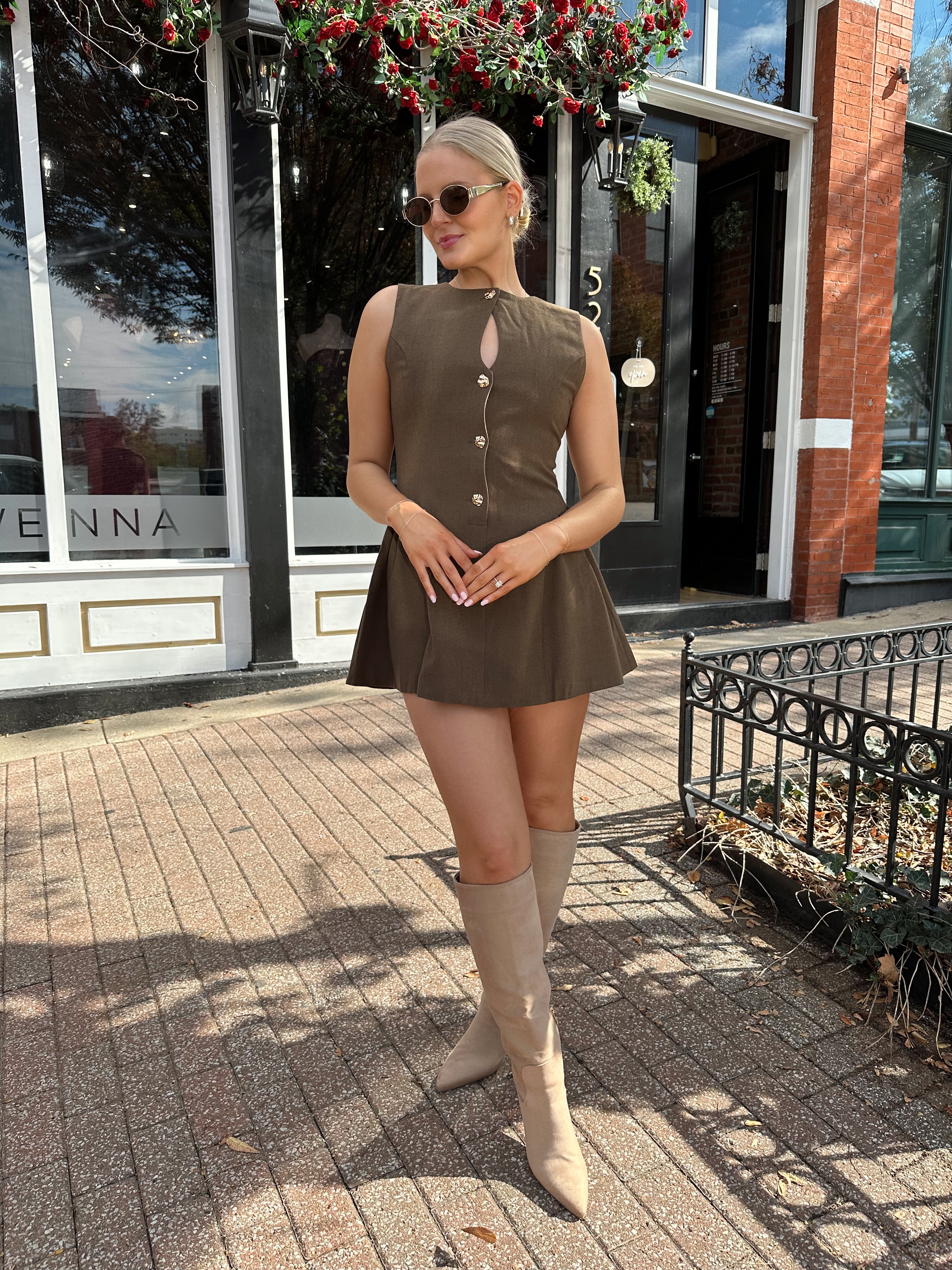 Woman wearing brown fit to flare mini dress with keyhole cutout and gold buttons.