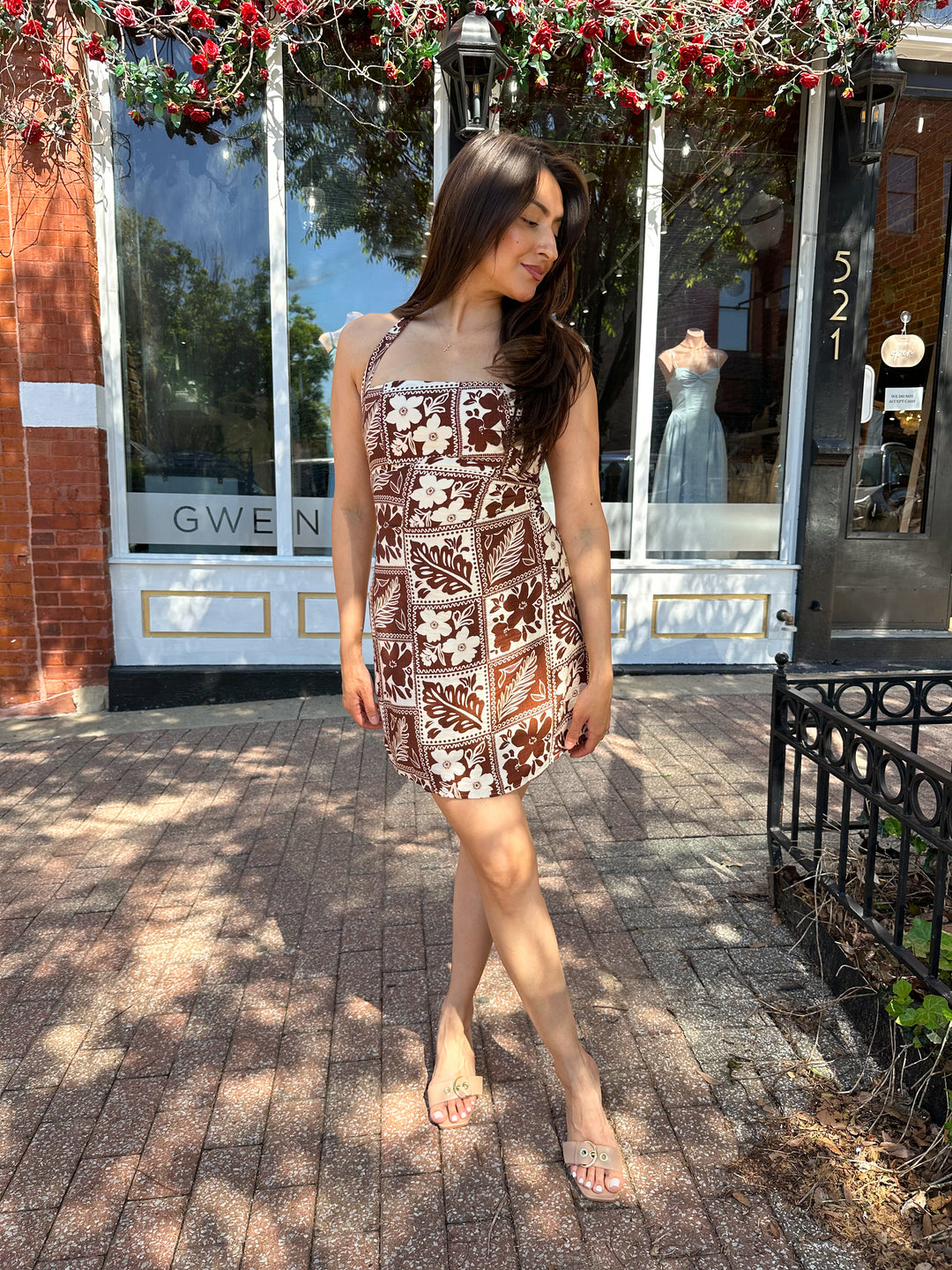 Woman wearing white and brown tropical print mini dress with square neckline.