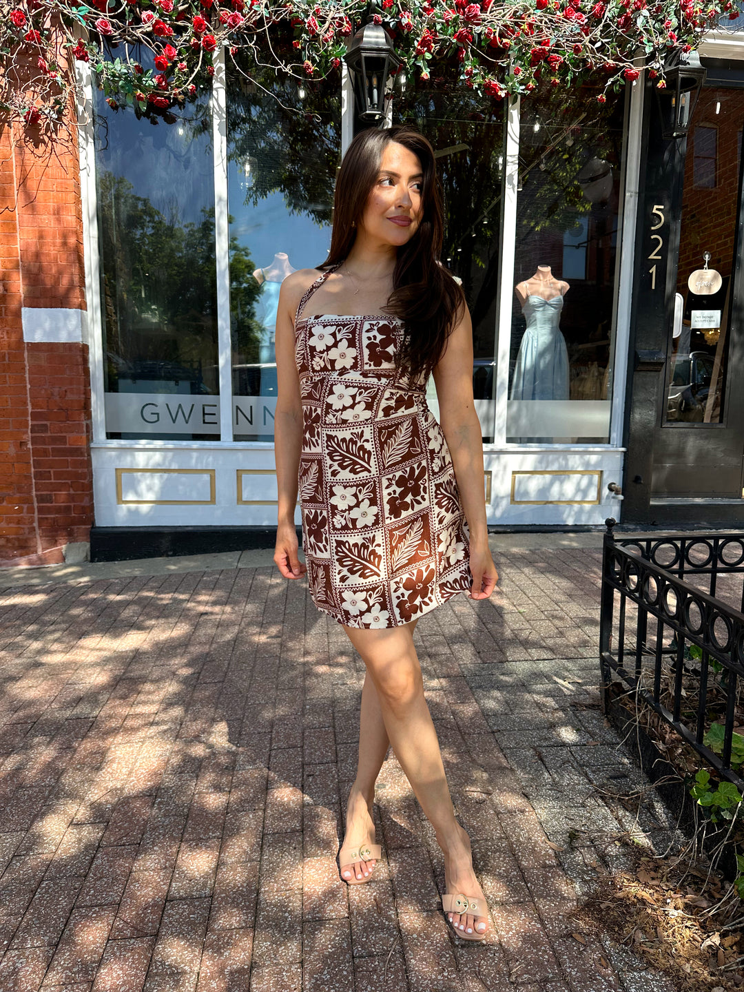 Woman wearing white and brown tropical print mini dress with square neckline.