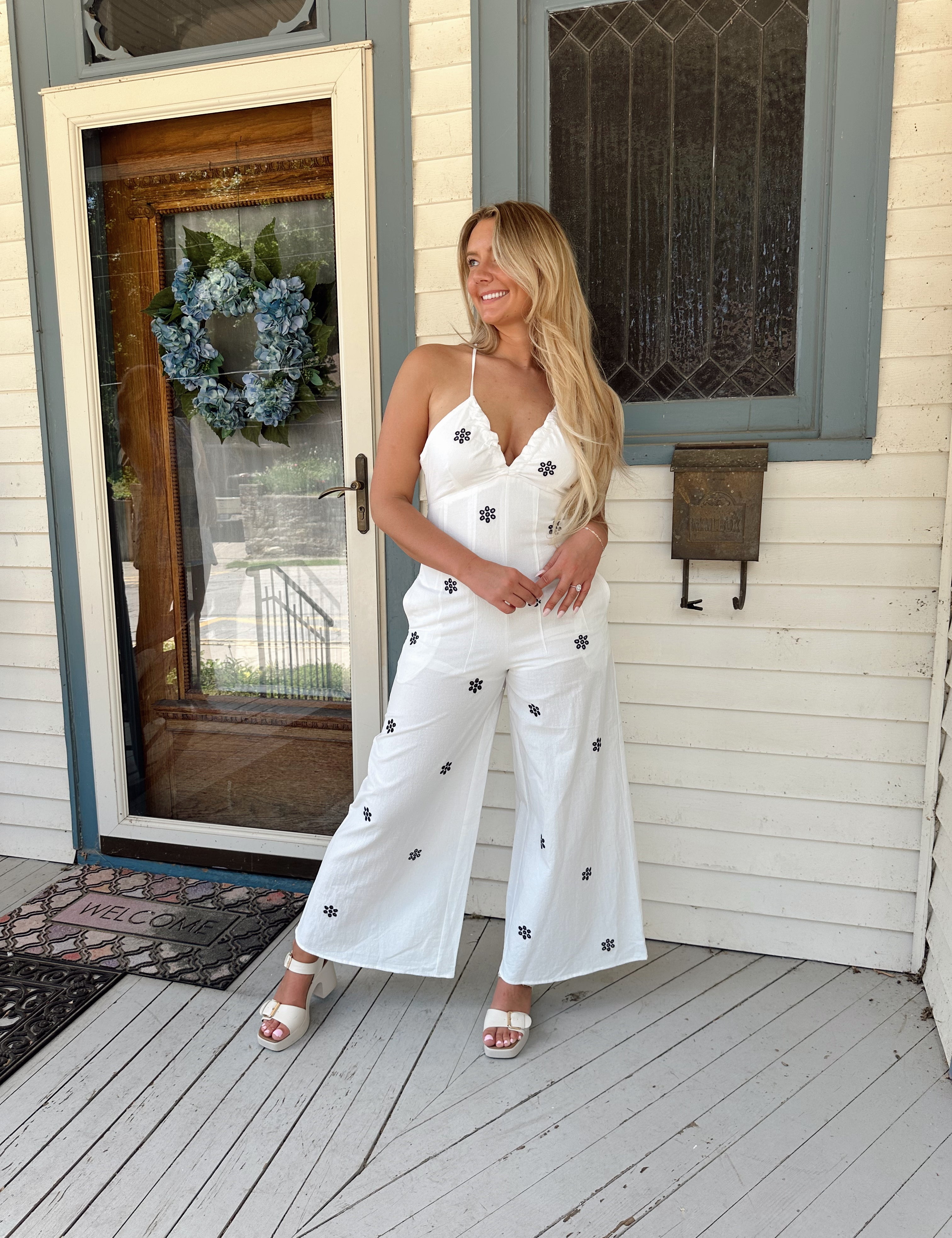 White wide leg jumpsuit with embroidered flowers. Self tie open back. 