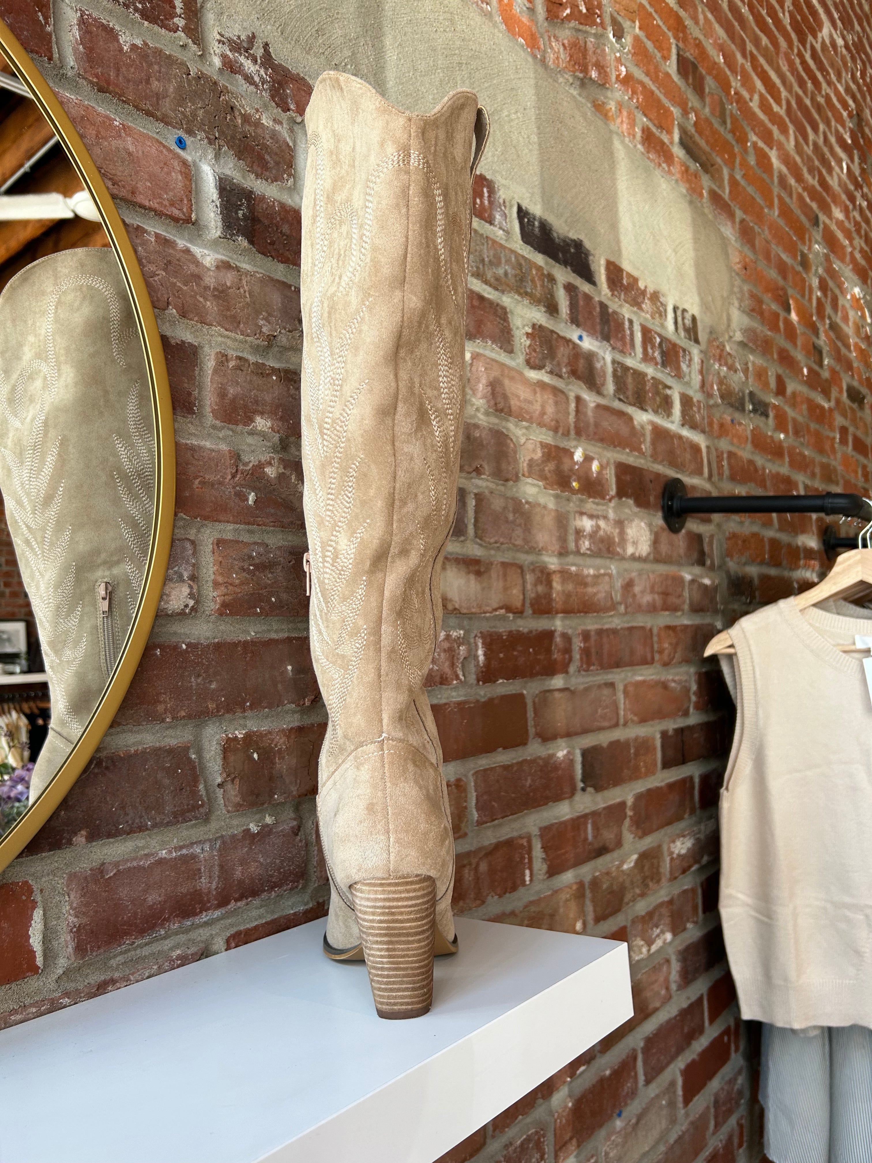 Tan suede tall Western boot with embroidered stitching, pointed toe, and stacked block heel
