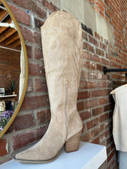 Tan suede tall Western boot with embroidered stitching, pointed toe, and stacked block heel
