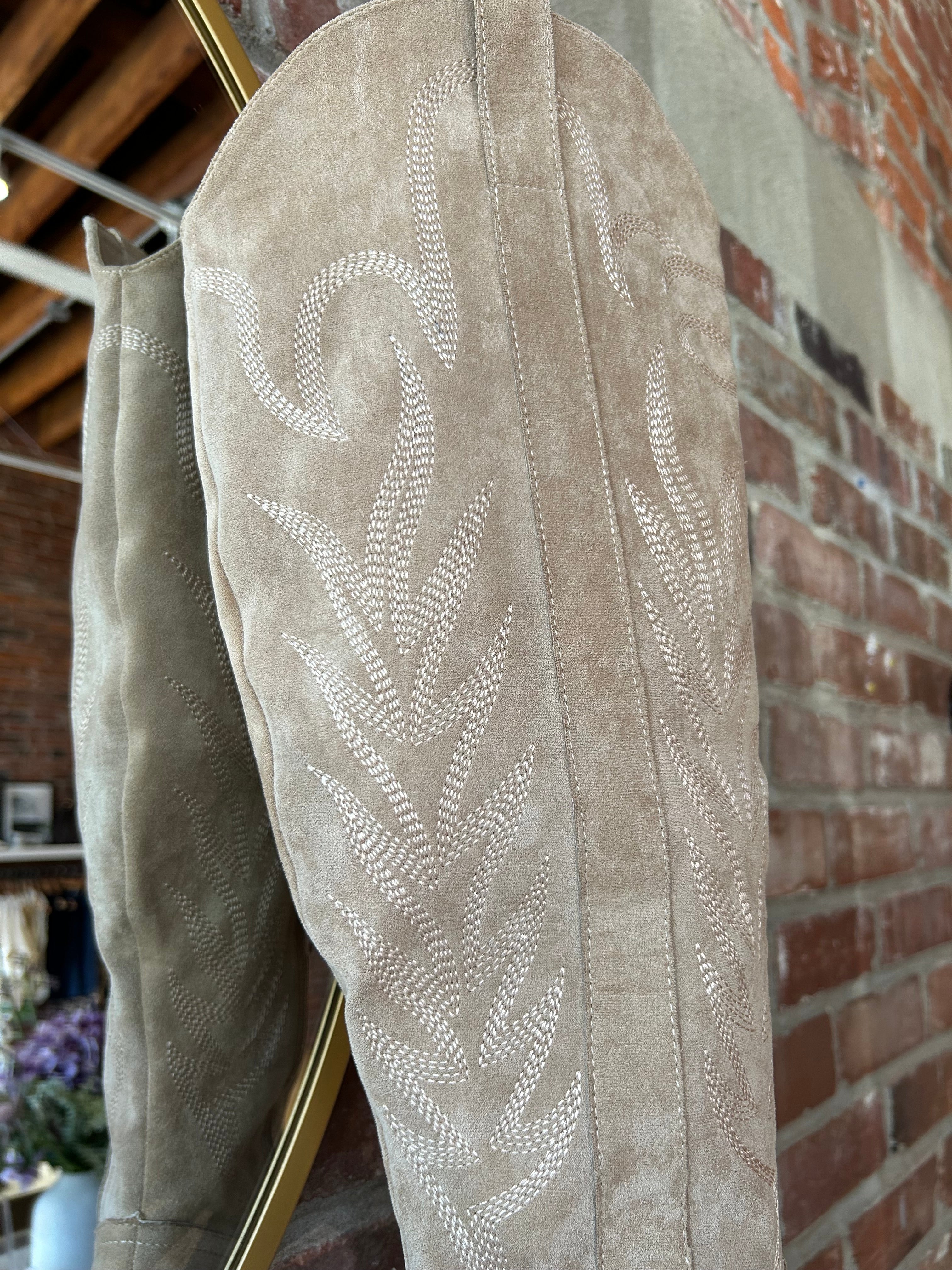 Tan suede tall Western boot with embroidered stitching, pointed toe, and stacked block heel
