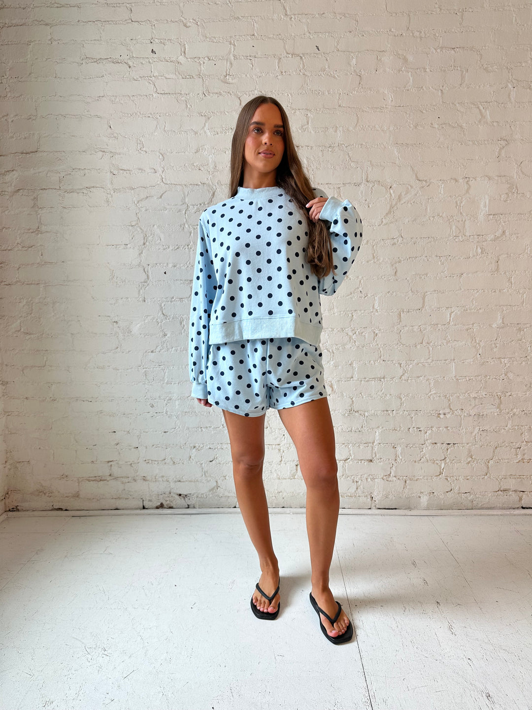 Woman wearing light blue two piece lounge set with navy polka dots. 