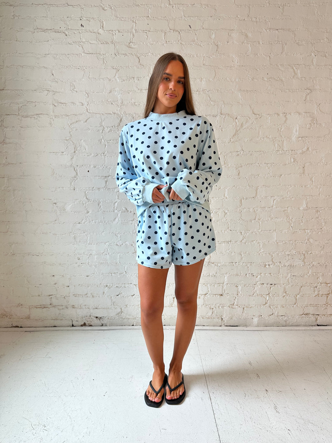 Woman wearing light blue two piece lounge set with navy polka dots. 