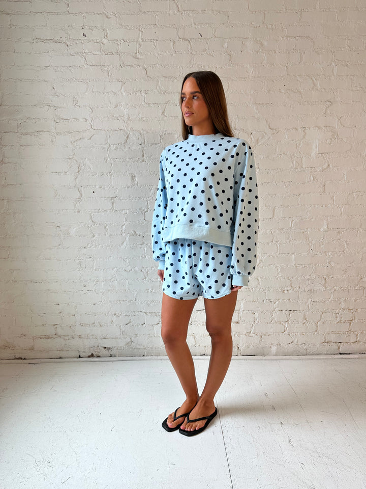Woman wearing light blue two piece lounge set with navy polka dots. 