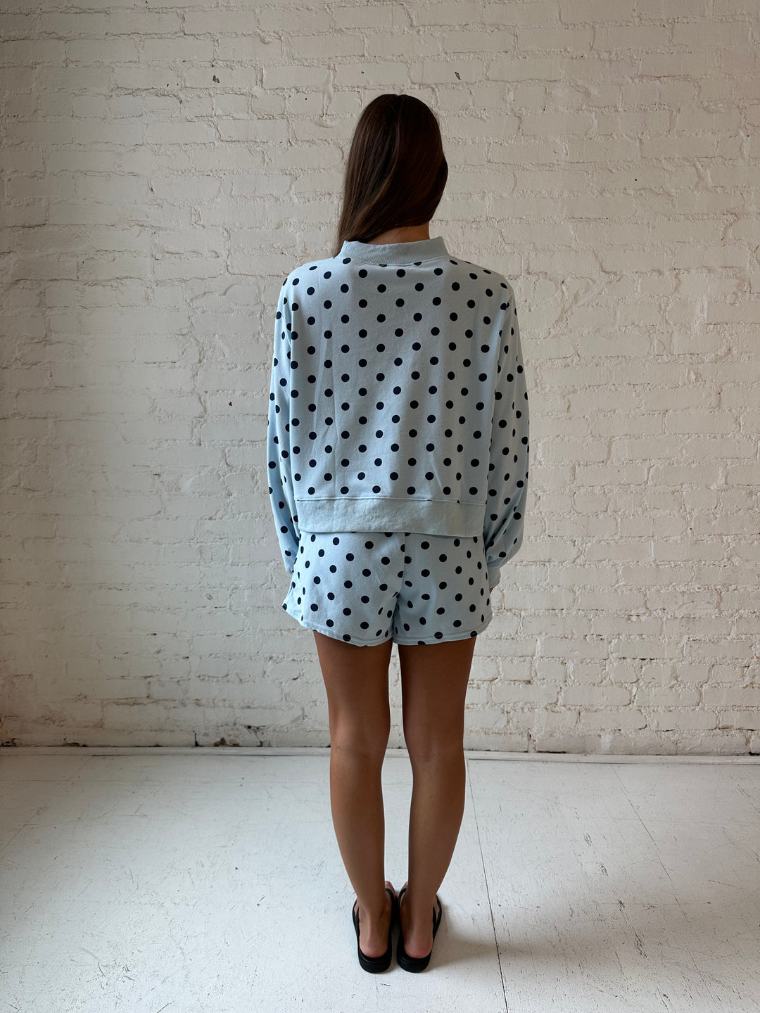 Woman wearing light blue two piece lounge set with navy polka dots. 