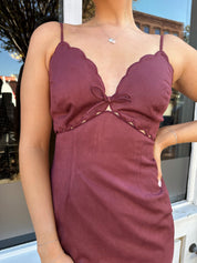 Woman wearing burgundy suede mini dress with scallop detail.