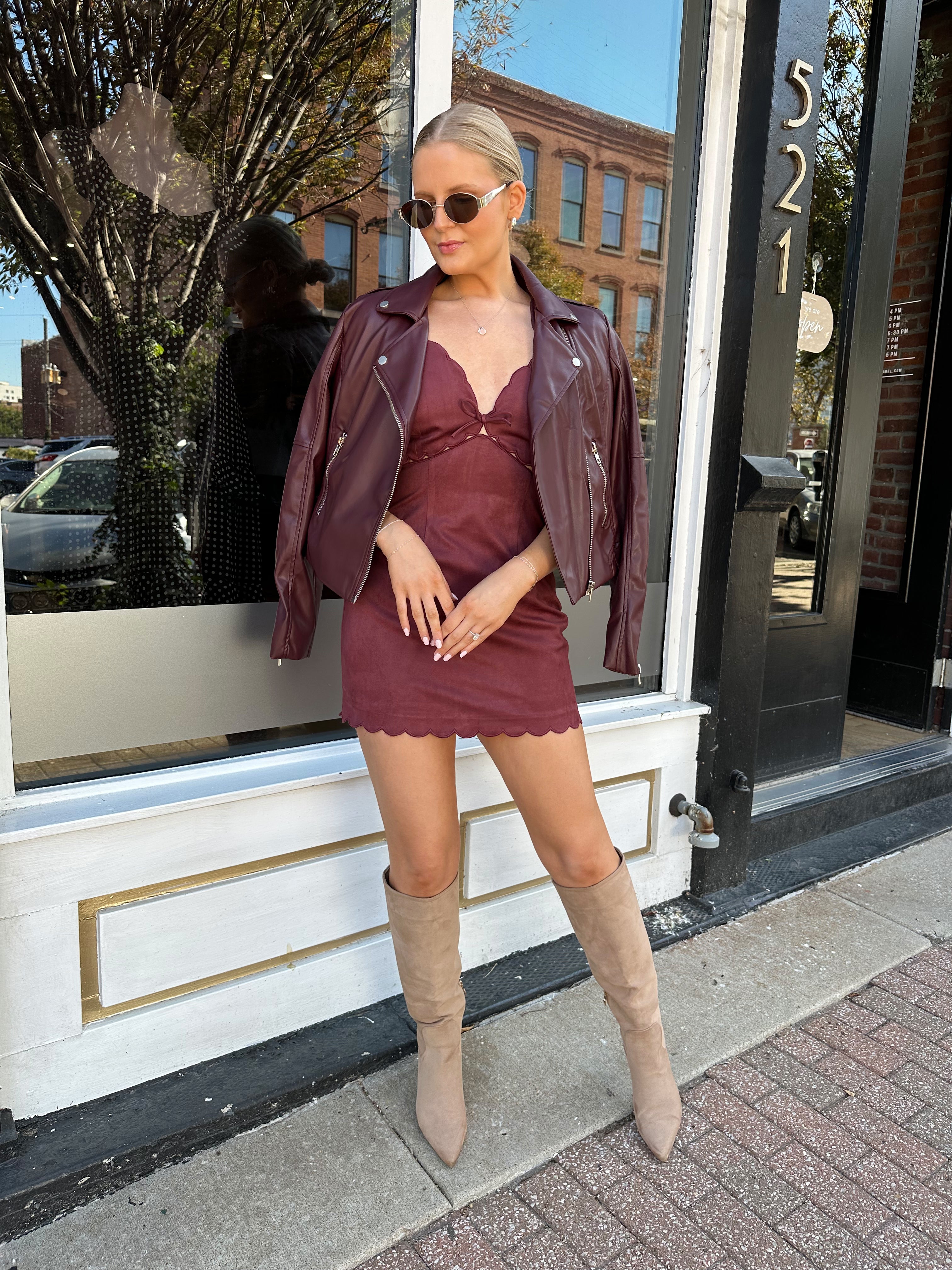 Woman wearing burgundy suede mini dress with scallop detail.