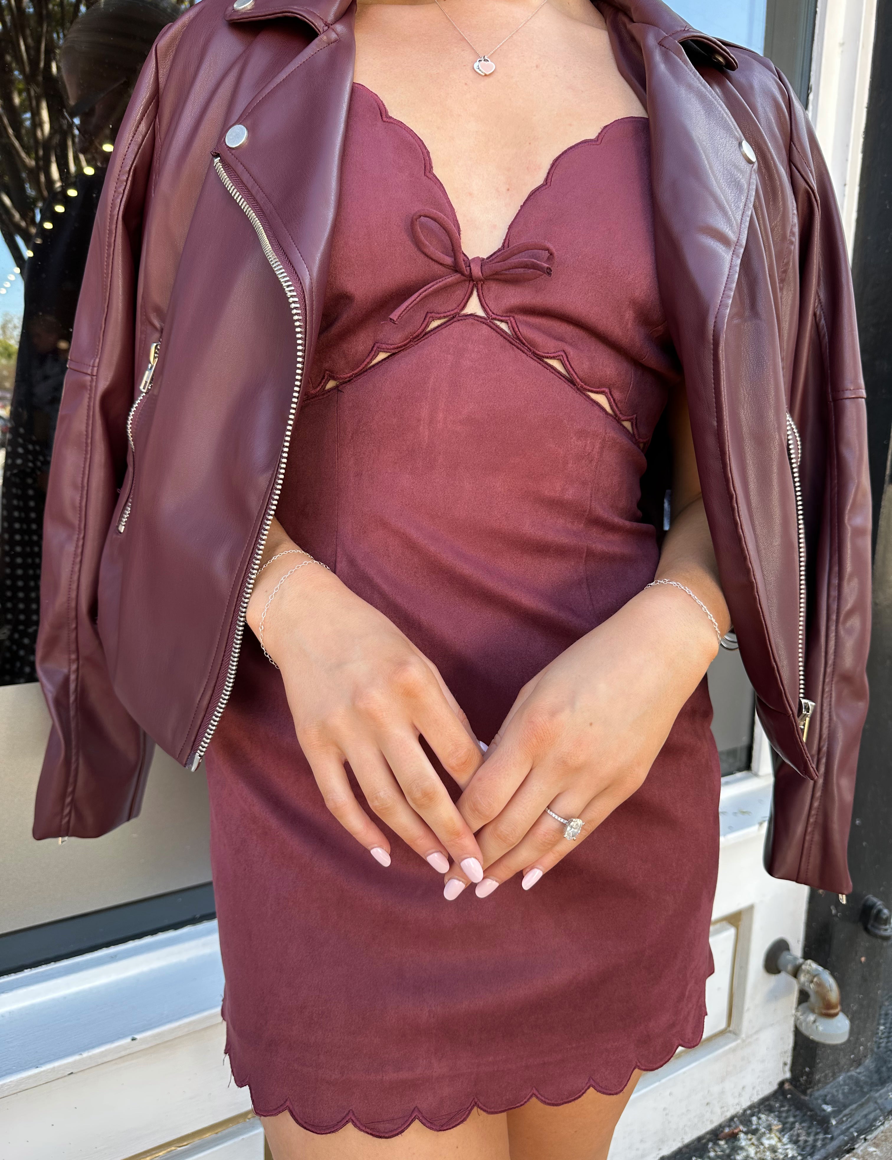 Woman wearing burgundy suede mini dress with scallop detail.
