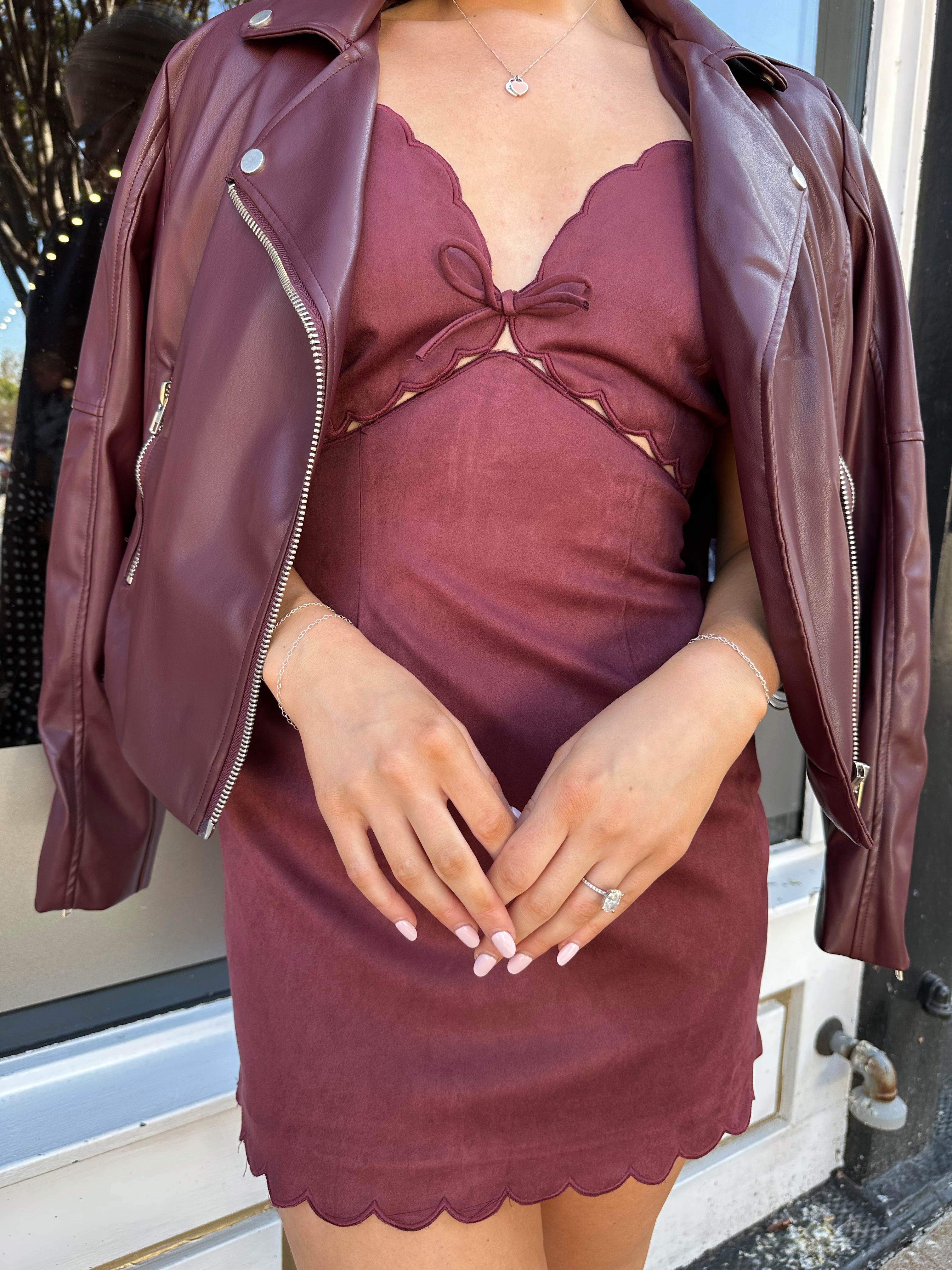 Woman wearing burgundy suede mini dress with scallop detail.