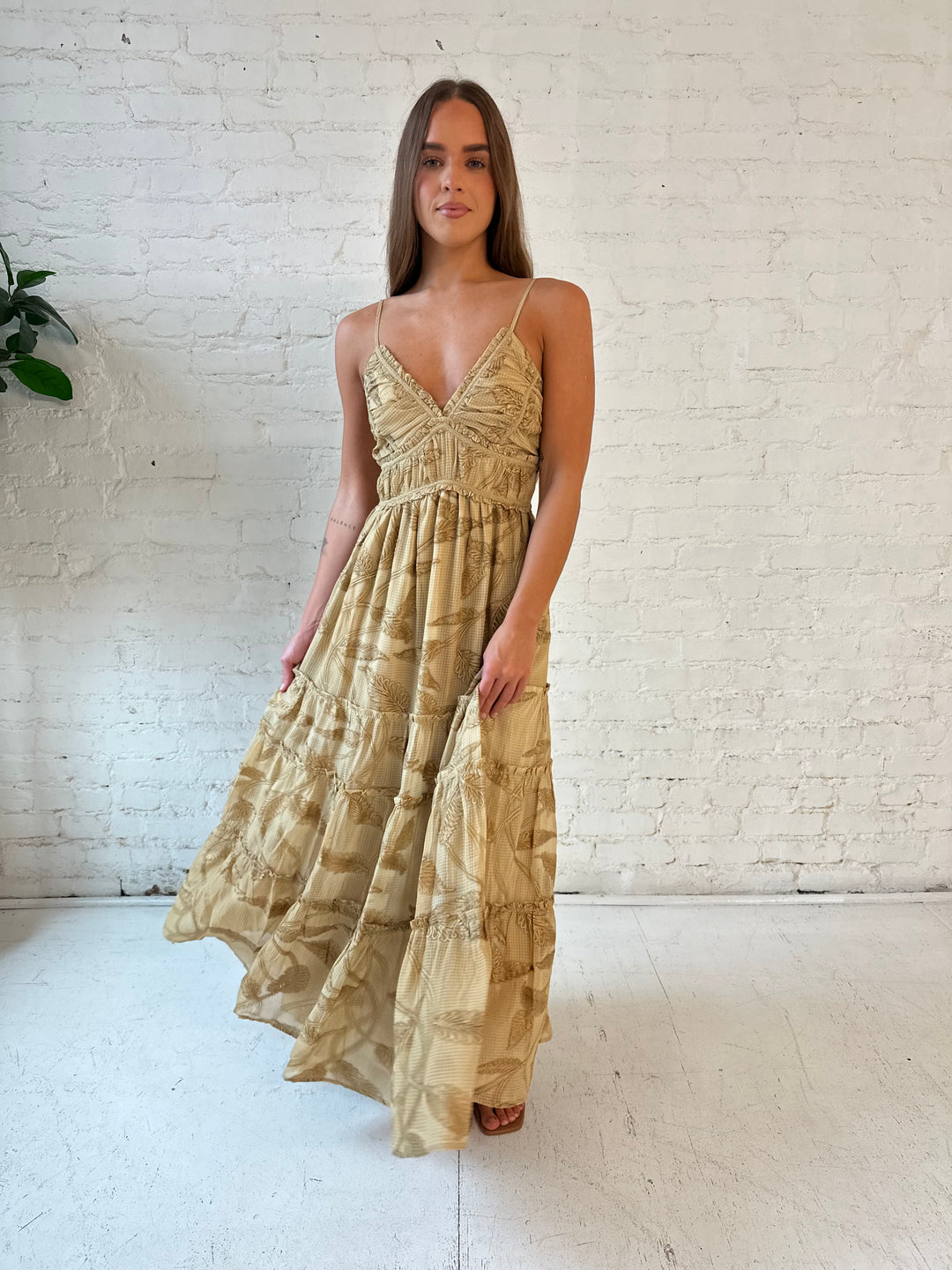 Woman wearing beige floral tiered maxi dress with gathered trim detail and smocked back. 