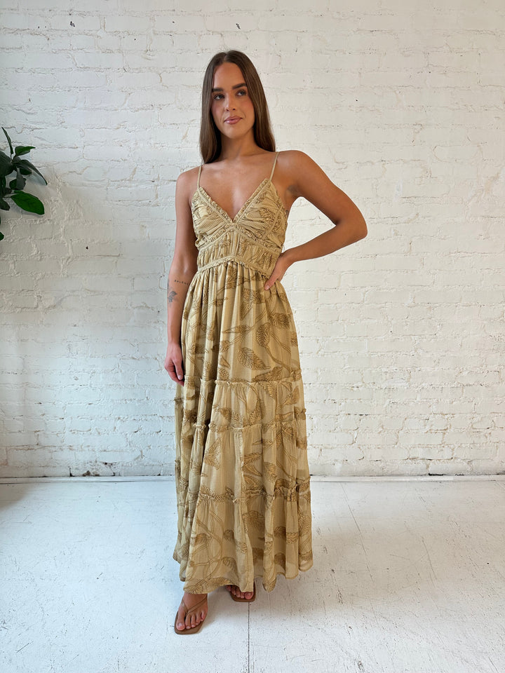 Woman wearing beige floral tiered maxi dress with gathered trim detail and smocked back. 