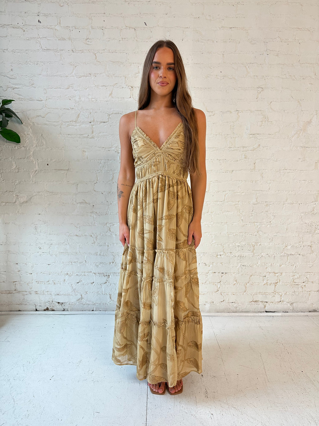 Woman wearing beige floral tiered maxi dress with gathered trim detail and smocked back. 