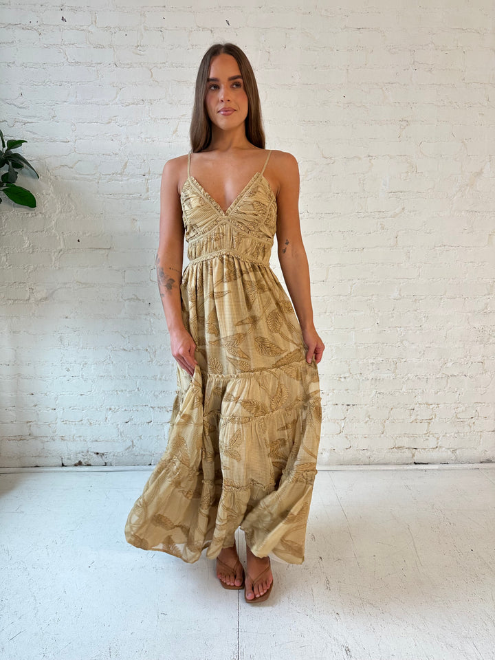 Woman wearing beige floral tiered maxi dress with gathered trim detail and smocked back. 