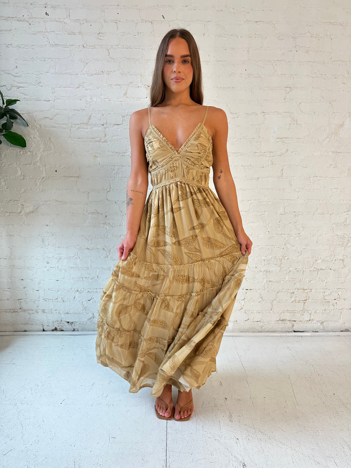 Woman wearing beige floral tiered maxi dress with gathered trim detail and smocked back. 