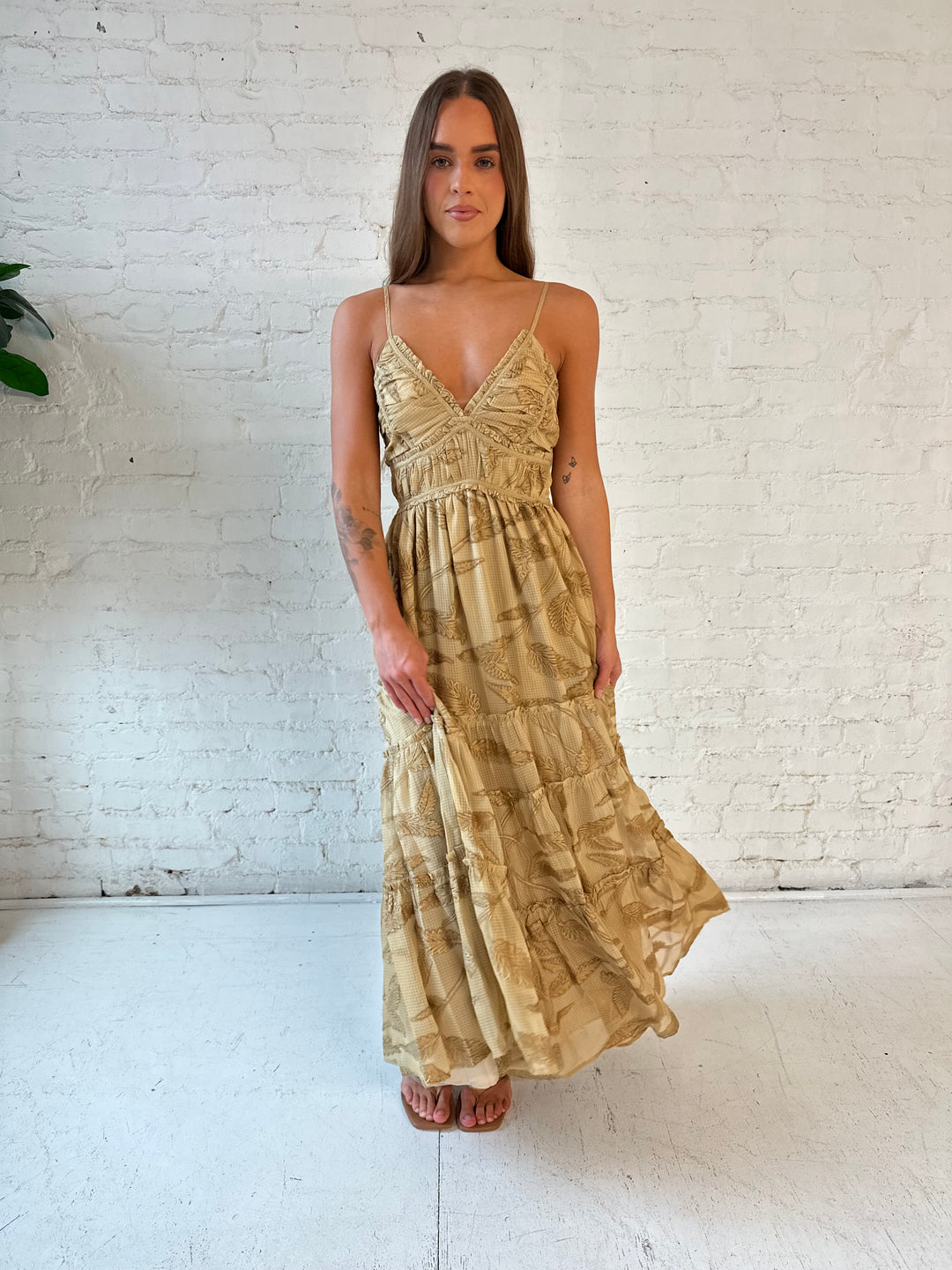 Woman wearing beige floral tiered maxi dress with gathered trim detail and smocked back. 