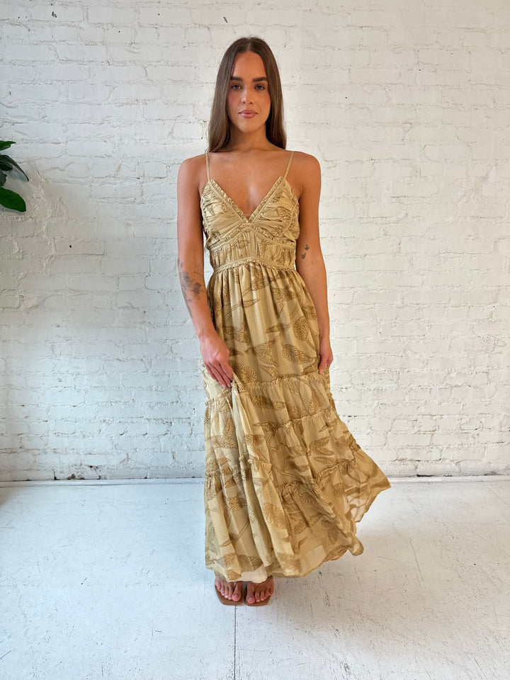 Woman wearing beige floral tiered maxi dress with gathered trim detail and smocked back. 