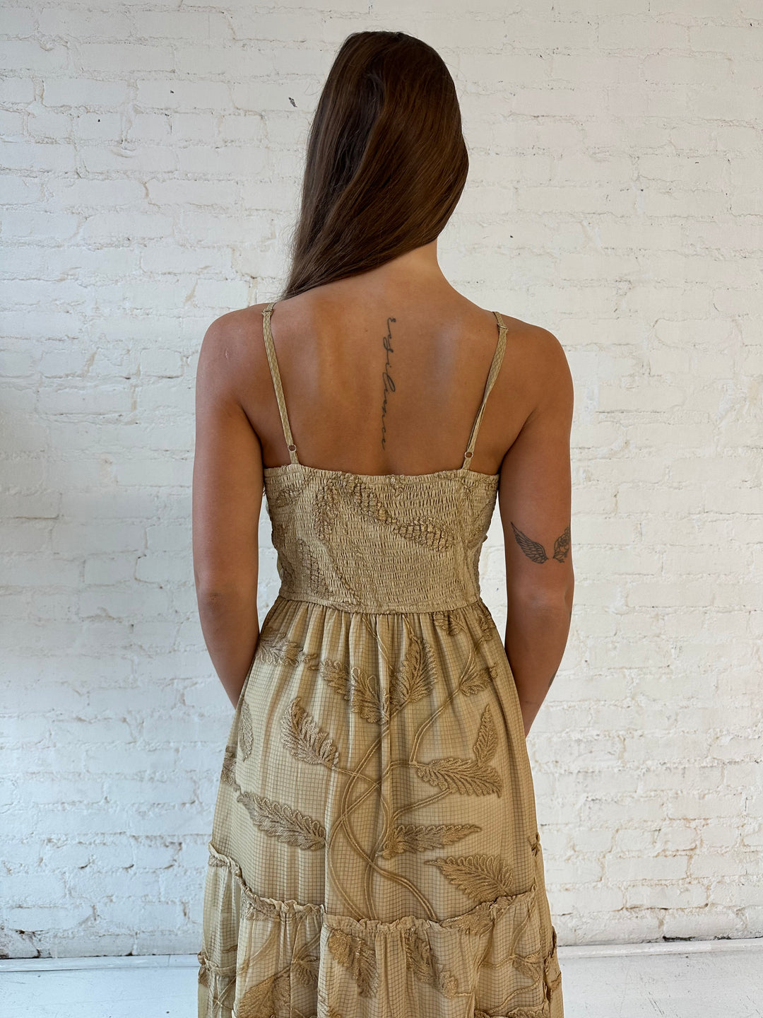 Woman wearing beige florall tiered maxi dress with gathered trim detail and smocked back. 