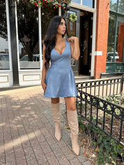 Woman wearing dusty blue suede fit to flare mini dress with v-neckline. 