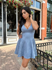 Woman wearing dusty blue suede fit to flare mini dress with v-neckline. 