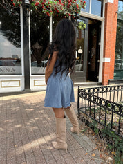 Woman wearing dusty blue suede fit to flare mini dress with v-neckline. 