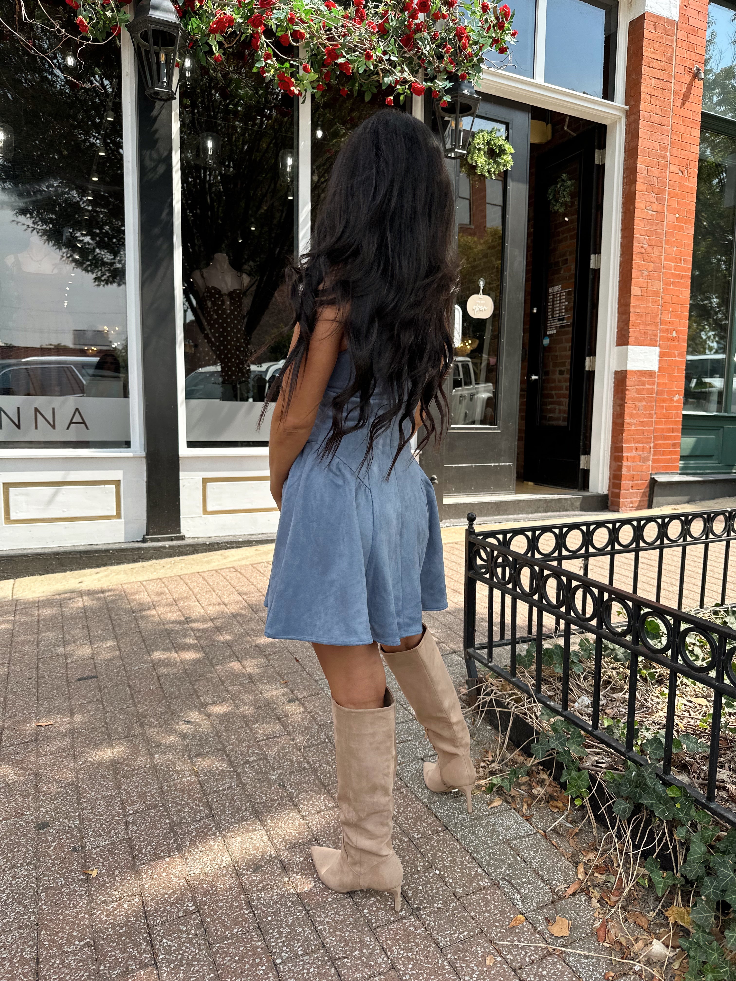 Woman wearing dusty blue suede fit to flare mini dress with v-neckline. 