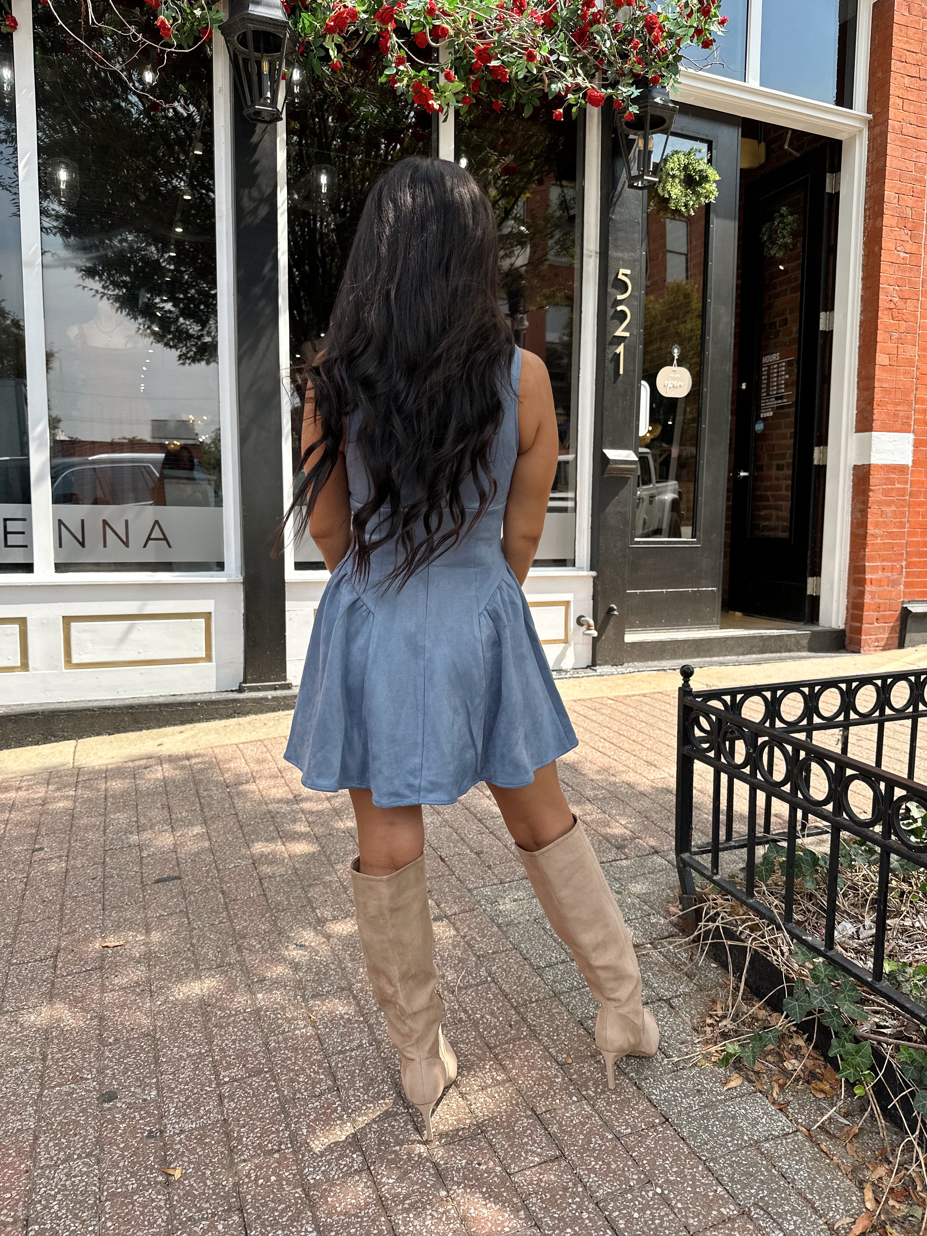 Woman wearing dusty blue suede fit to flare mini dress with v-neckline. 