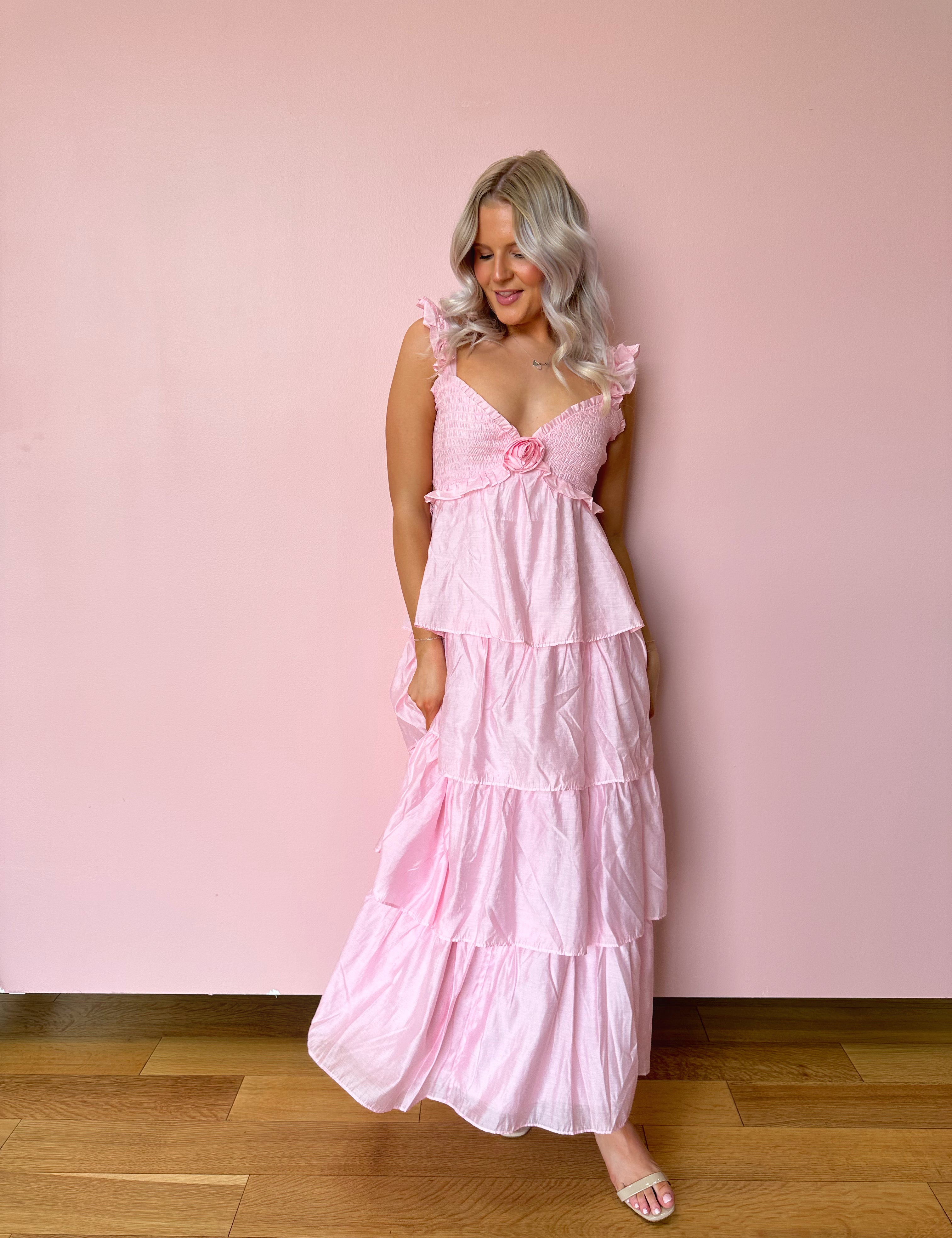 Pink tiered maxi dress with rosette detail. Perfect for any special occasions. 
