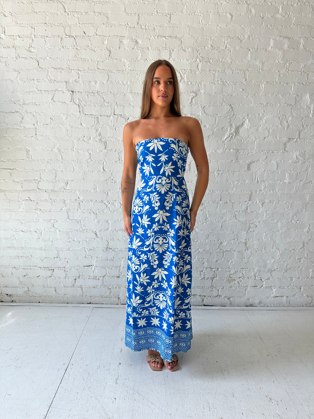 Woman wearing blue tropical print strapless maxi dress. 