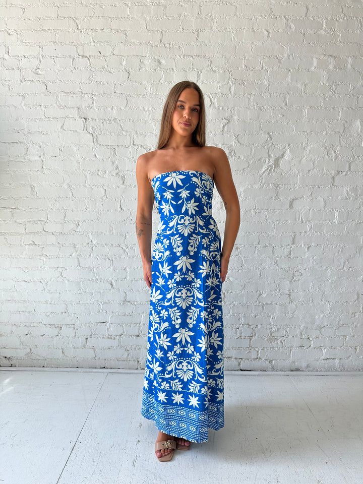 Woman wearing blue tropical print strapless maxi dress. 