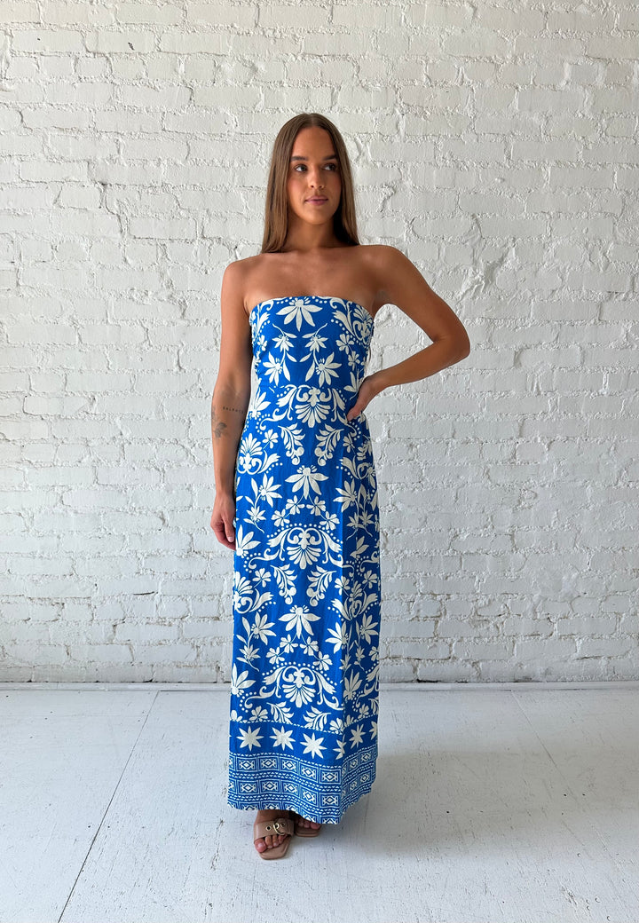Woman wearing blue tropical print strapless maxi dress. 