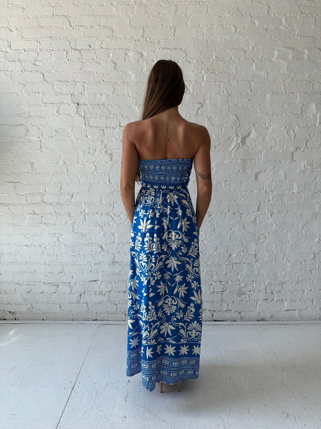 Woman wearing blue tropical print strapless maxi dress. 