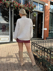 Woman wearing burgundy leather mini dress with stone knit turtle neck sweater.