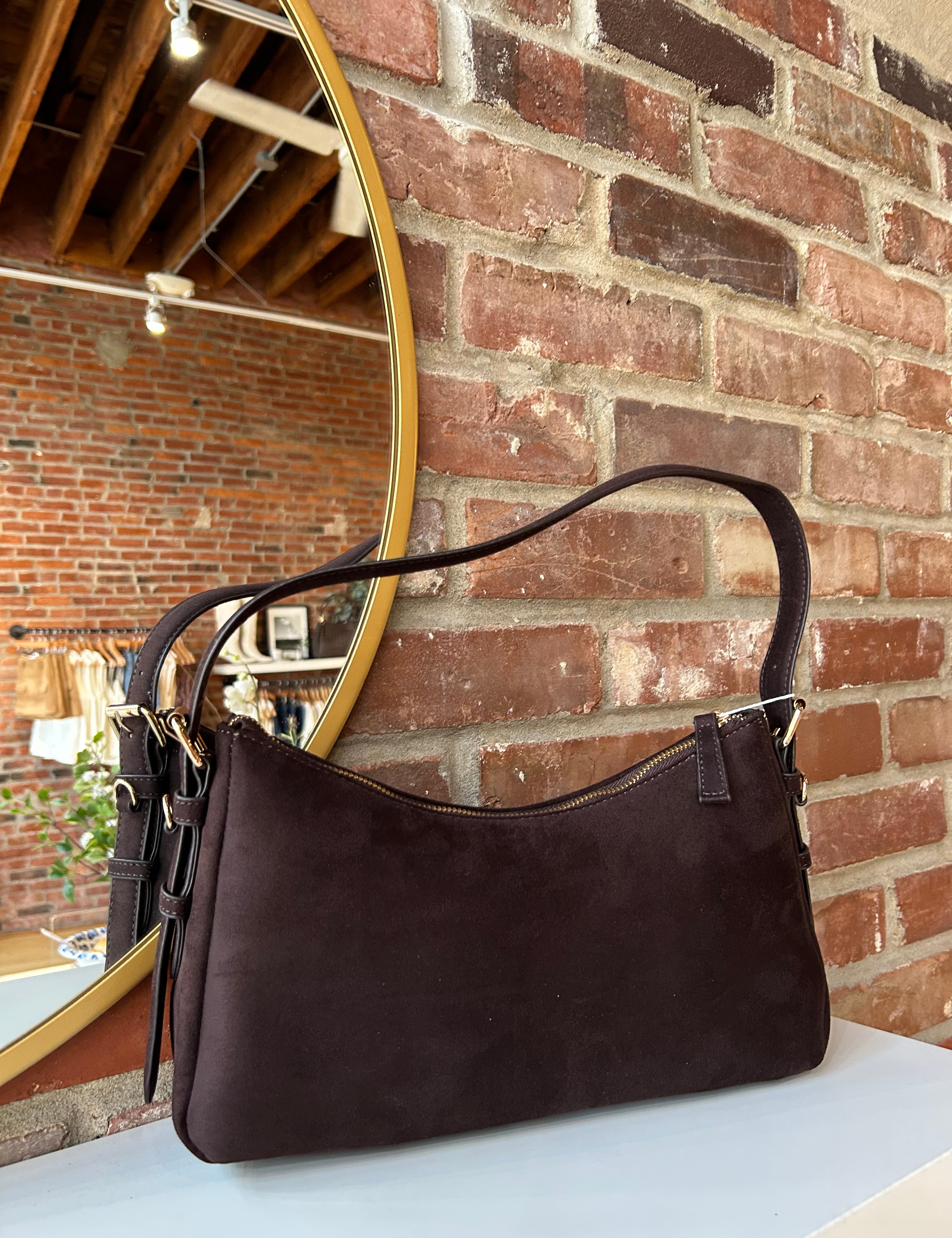 Dark brown suede shoulder bag with adjustable strap and gold hardware. 