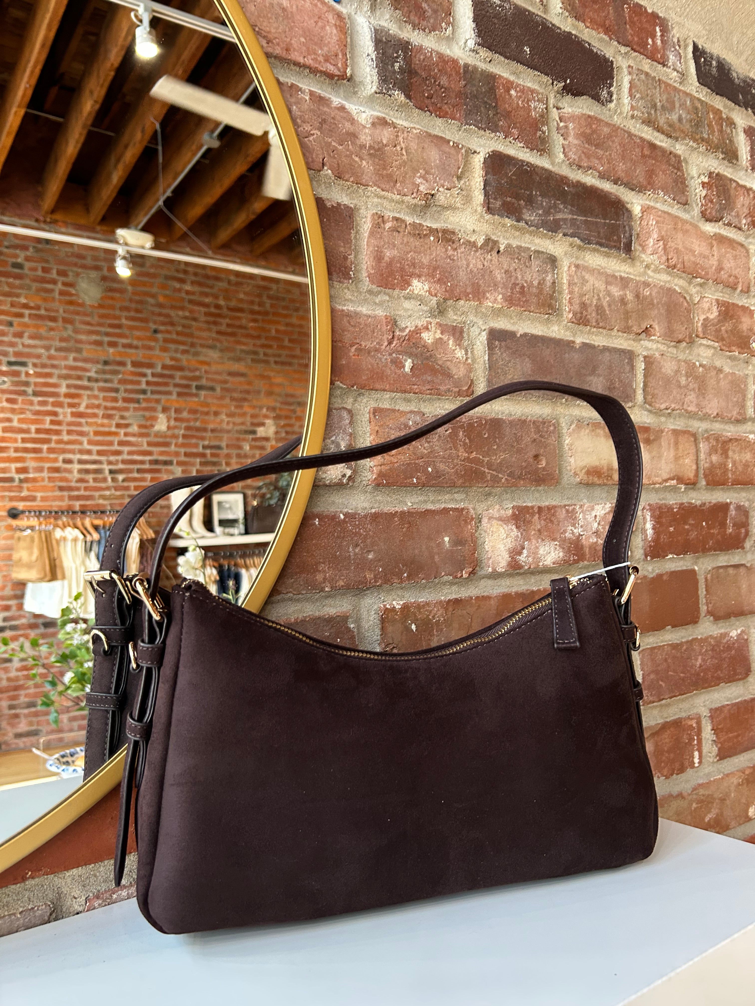 Dark brown suede shoulder bag with adjustable strap and gold hardware. 