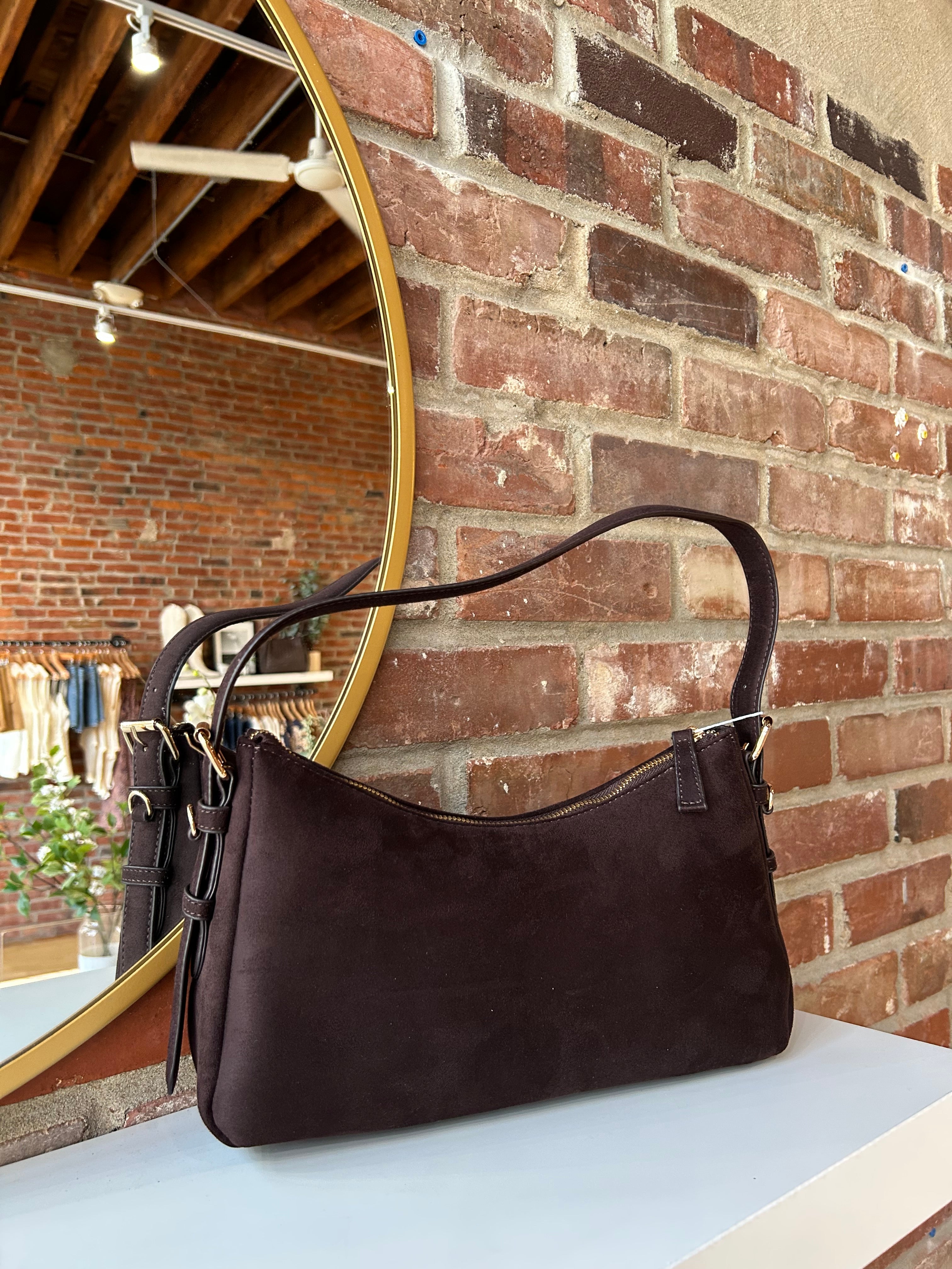 Dark brown suede shoulder bag with adjustable strap and gold hardware. 