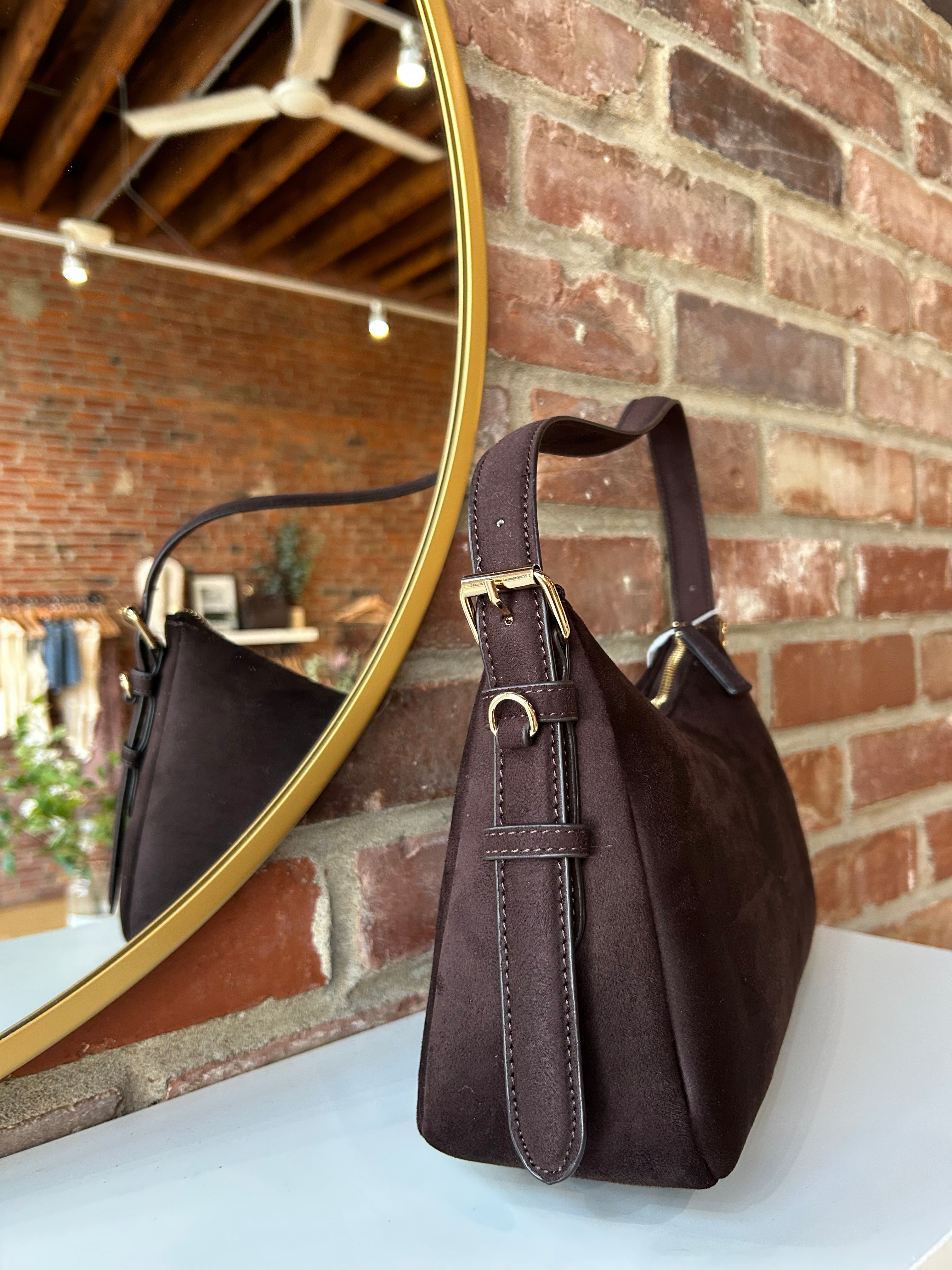 Dark brown suede shoulder bag with adjustable strap and gold hardware. 