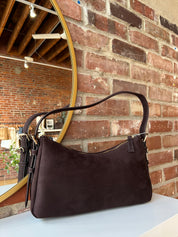 Dark brown suede shoulder bag with adjustable strap and gold hardware. 