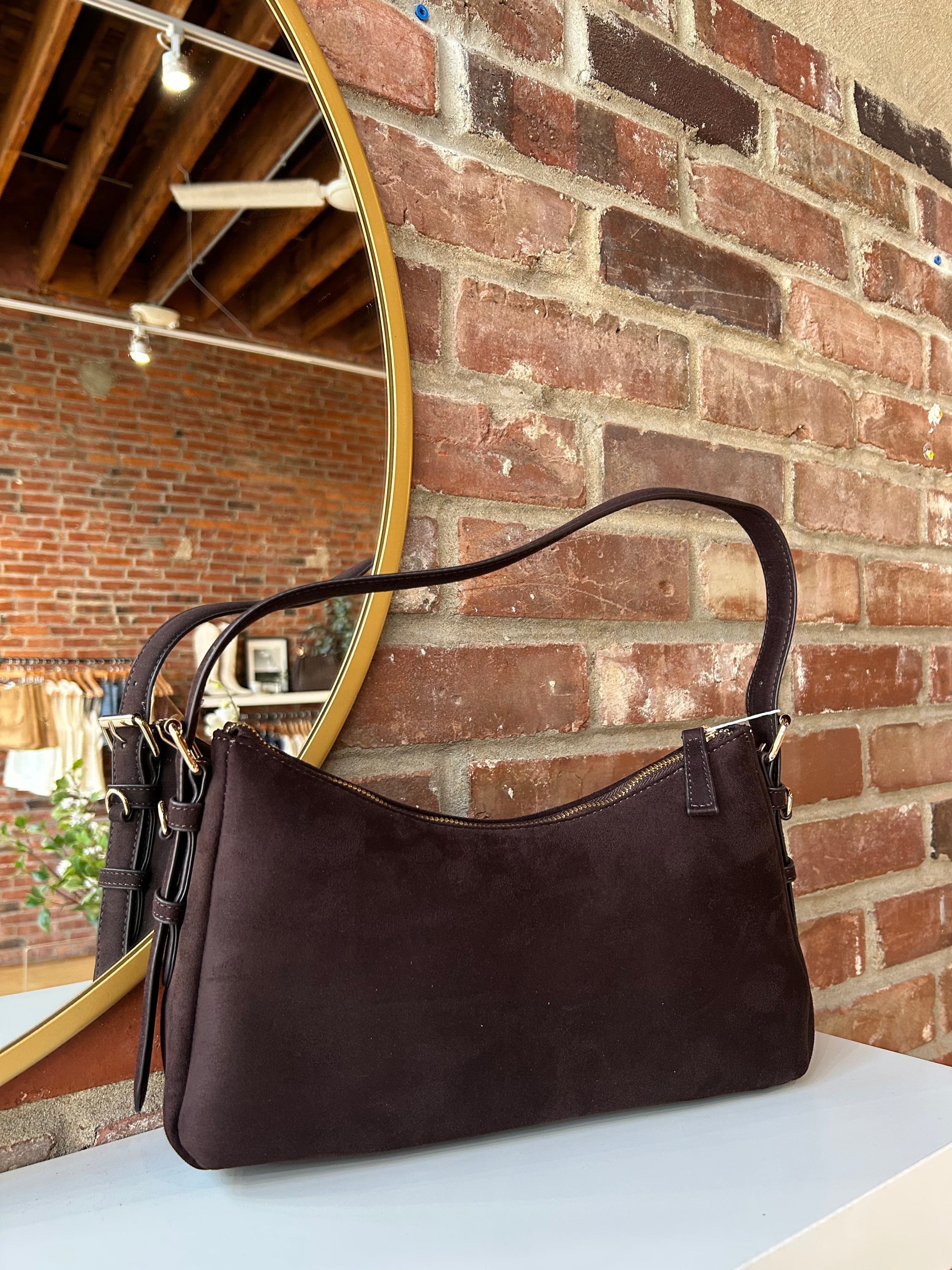 Dark brown suede shoulder bag with adjustable strap and gold hardware. 