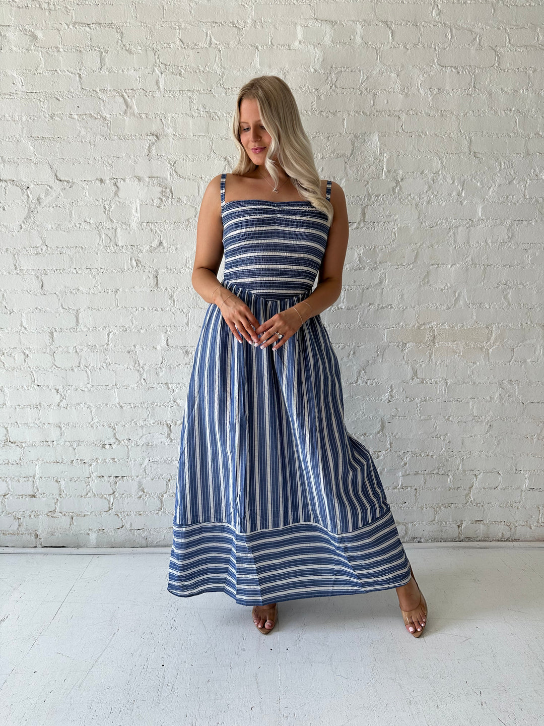 Woman wearing blue striped maxi dress with a smocked bodice, and adjustable straps. 