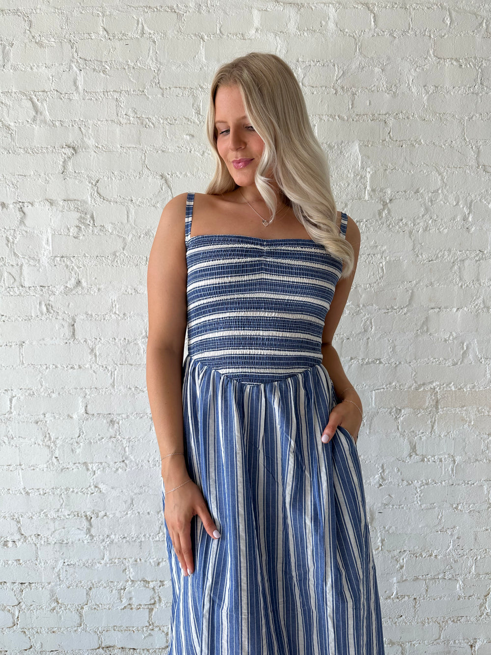 Woman wearing blue striped maxi dress with a smocked bodice, and adjustable straps. 