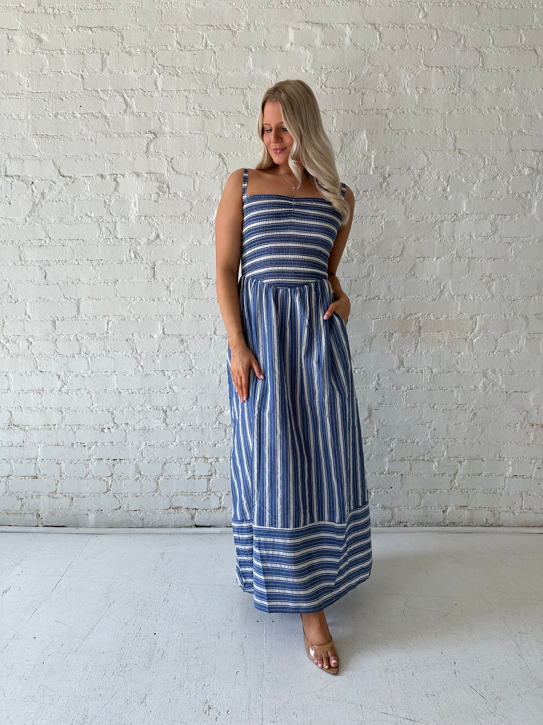 Woman wearing blue striped maxi dress with a smocked bodice, and adjustable straps. 