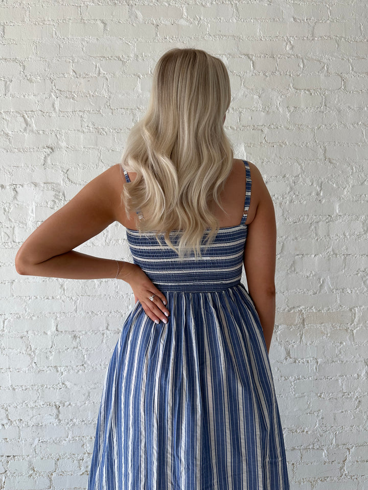 Woman wearing blue striped maxi dress with a smocked bodice, and adjustable straps. 