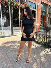 Woman wearing black asymmetrical mini dress with black heels.