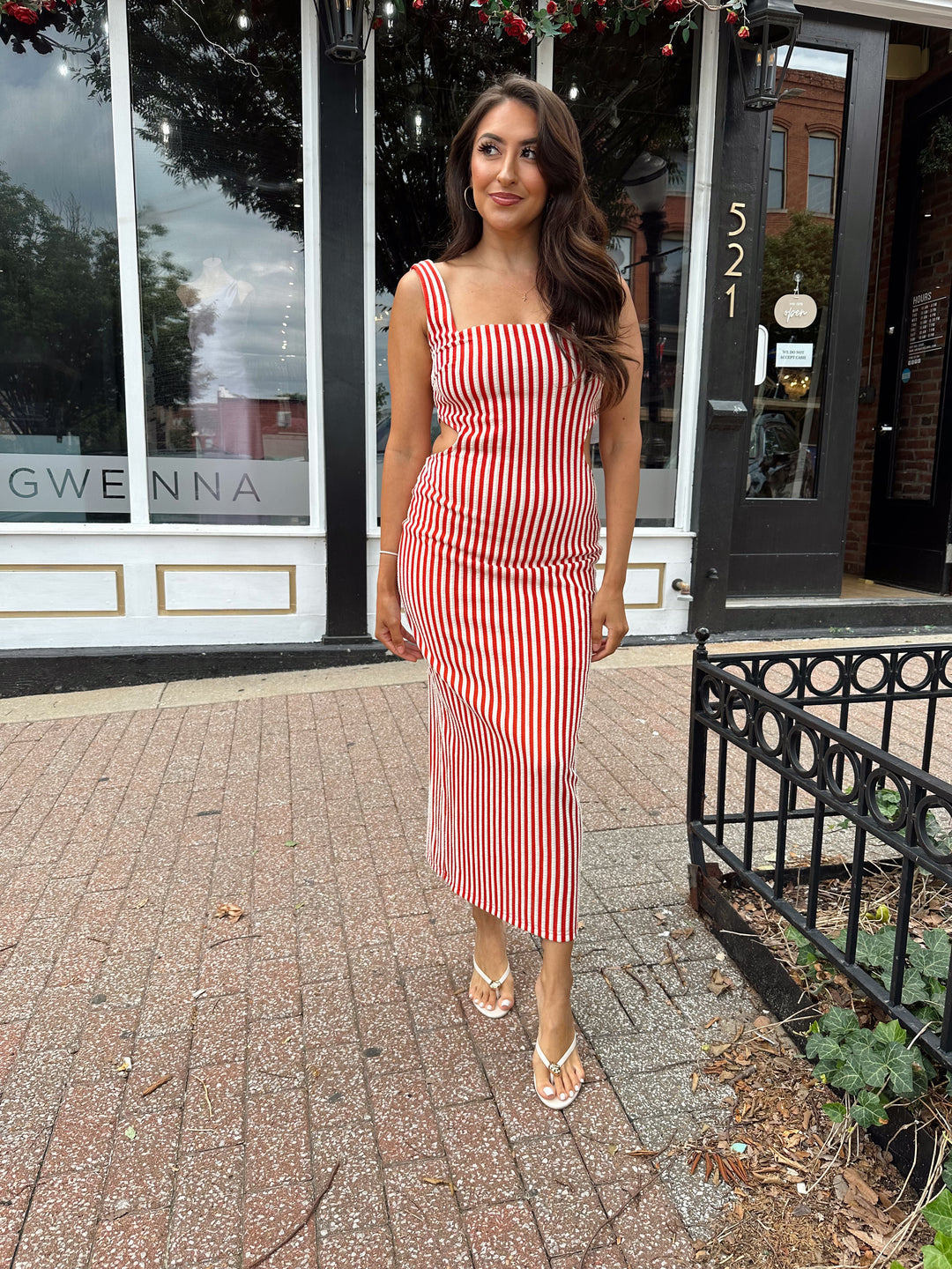 Woman wearing red and white striped textured midi dress with an open back. 