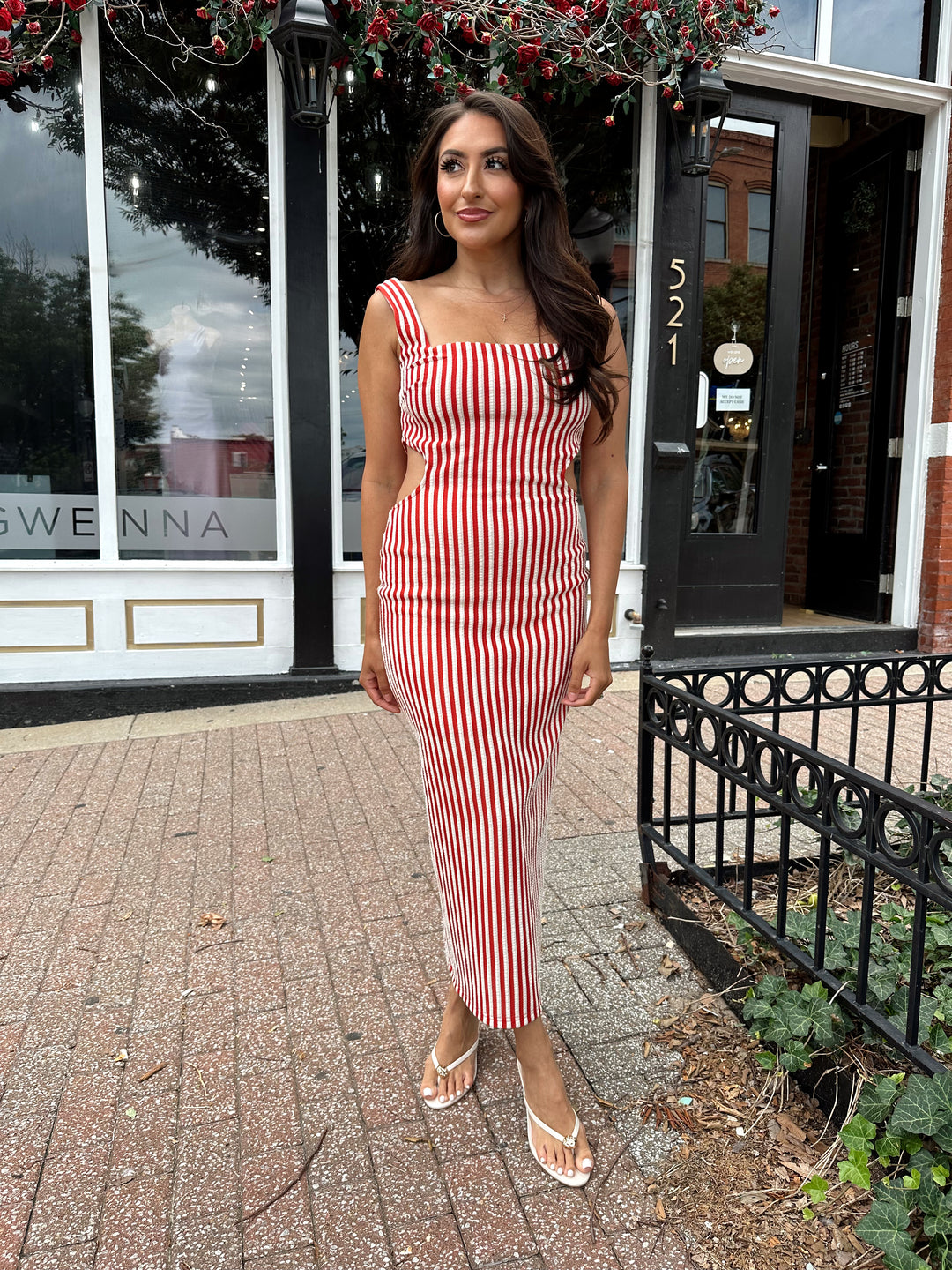 Woman wearing red and white striped textured midi dress with an open back. 