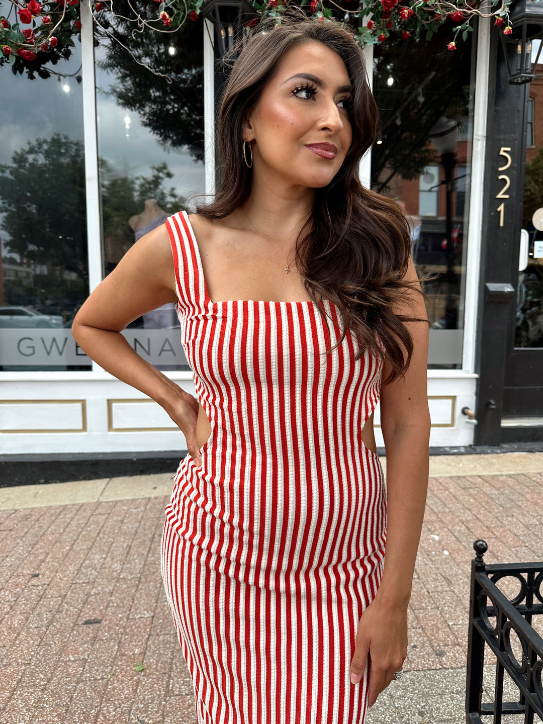 Woman wearing red and white striped textured midi dress with an open back. 